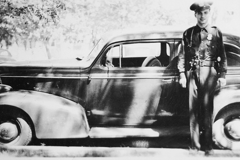 Dewey next to his patrol car